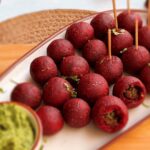 Deep ruby-red spicy beetroot thecha pops arranged on wooden board with peanuts