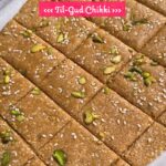 Square pieces of soft Til Gud Chikki (Sesame Jaggery Brittle) garnished with chopped cashew and sesame seeds